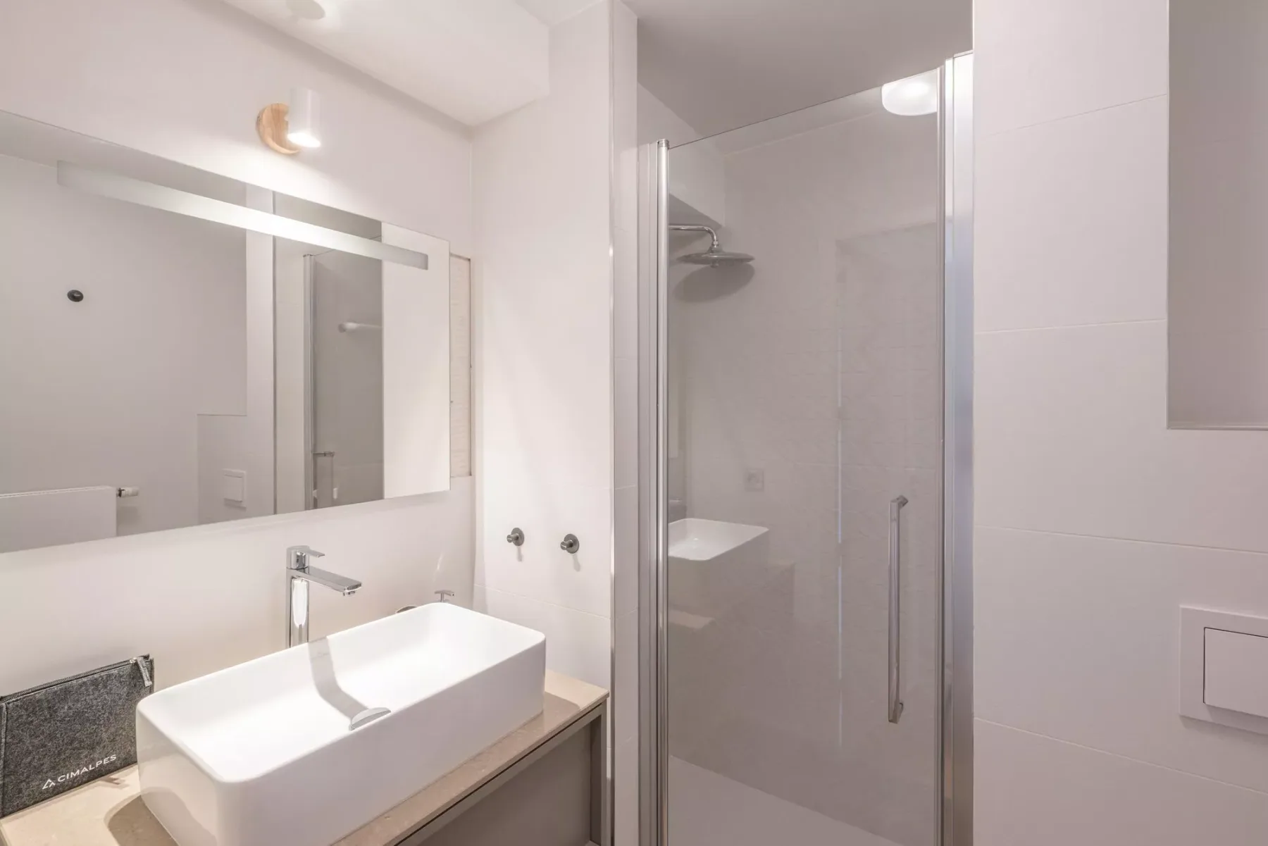 A bright bathroom with a sink, mirror, and glass shower.