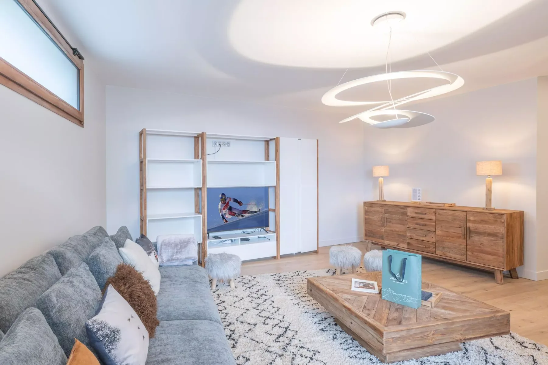A bright living room with seating, a wooden coffee table, and a television.