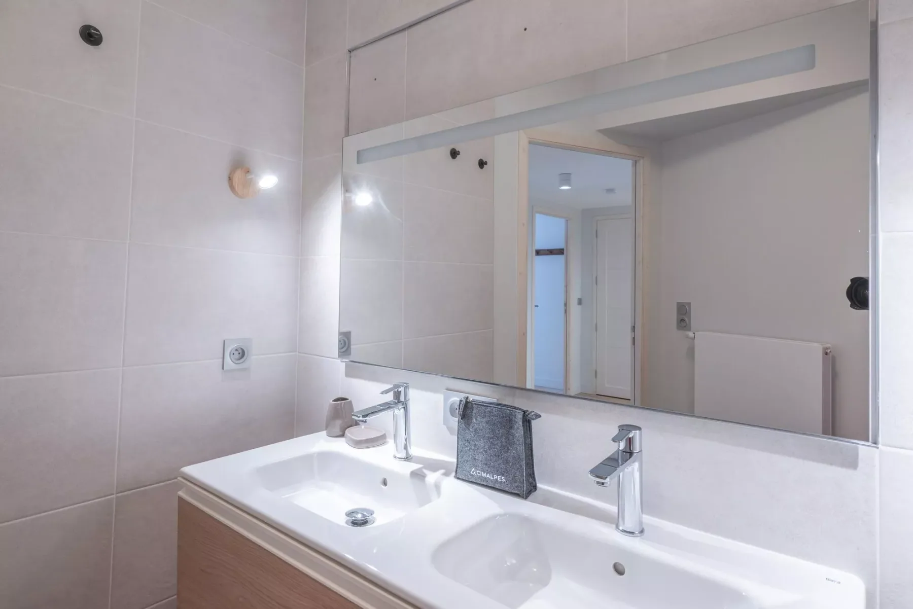 A bathroom vanity with a wide mirror and two sinks.
