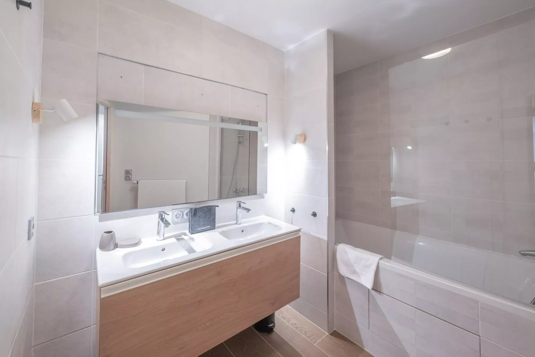 A tiled bathroom with a wide vanity and a bathtub.