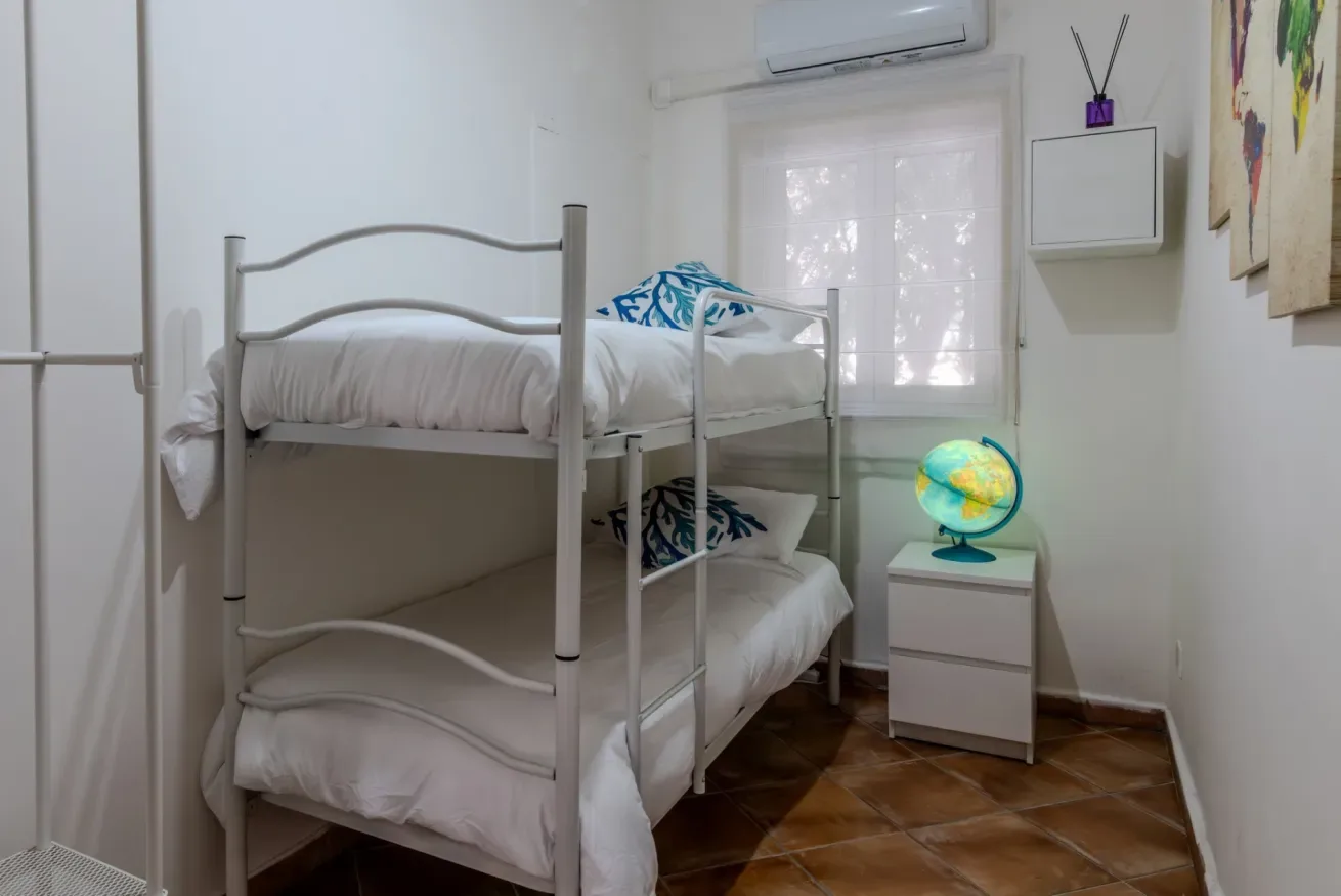 Una litera está junto a una ventana y una pequeña mesita de noche.
