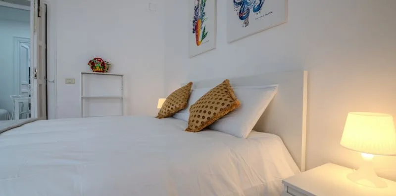 Un dormitorio con una cama bien tendida y una lámpara de noche.
