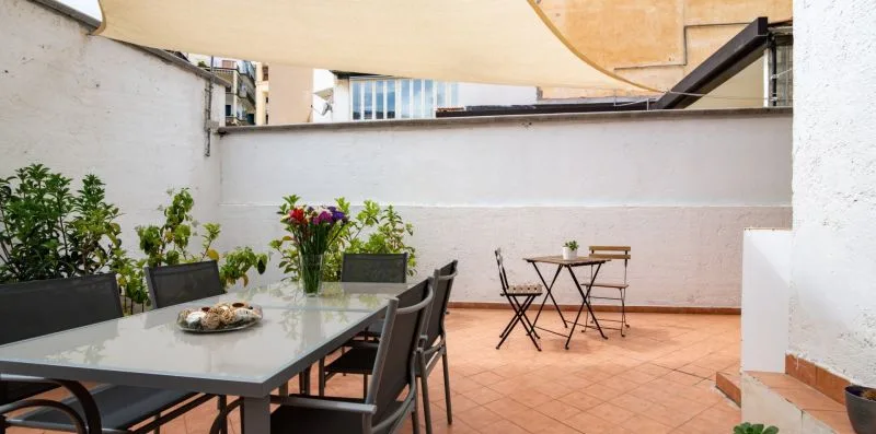Un comedor al aire libre con una mesa y asientos bajo un toldo.