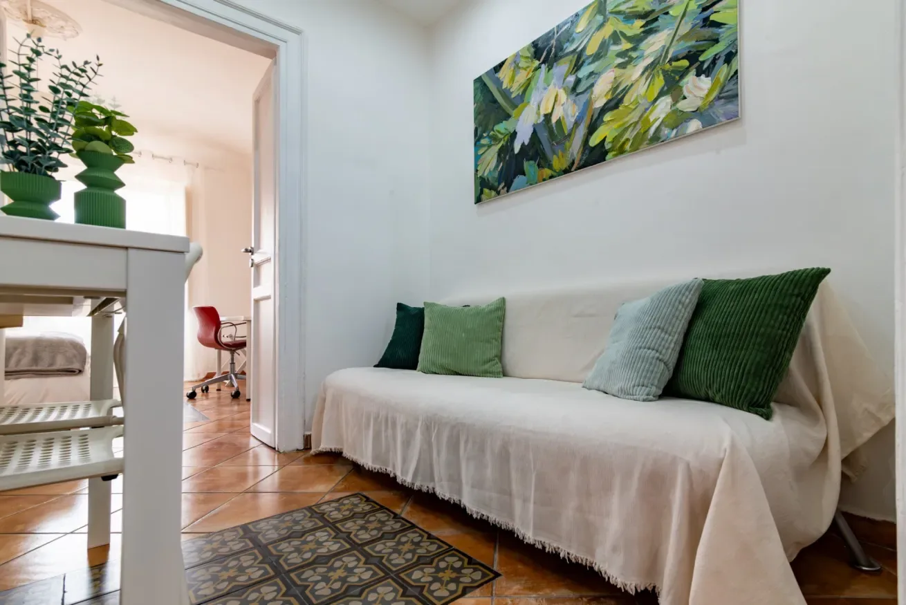 Una luminosa sala de estar con un sofá cubierto y una colorida obra abstracta.