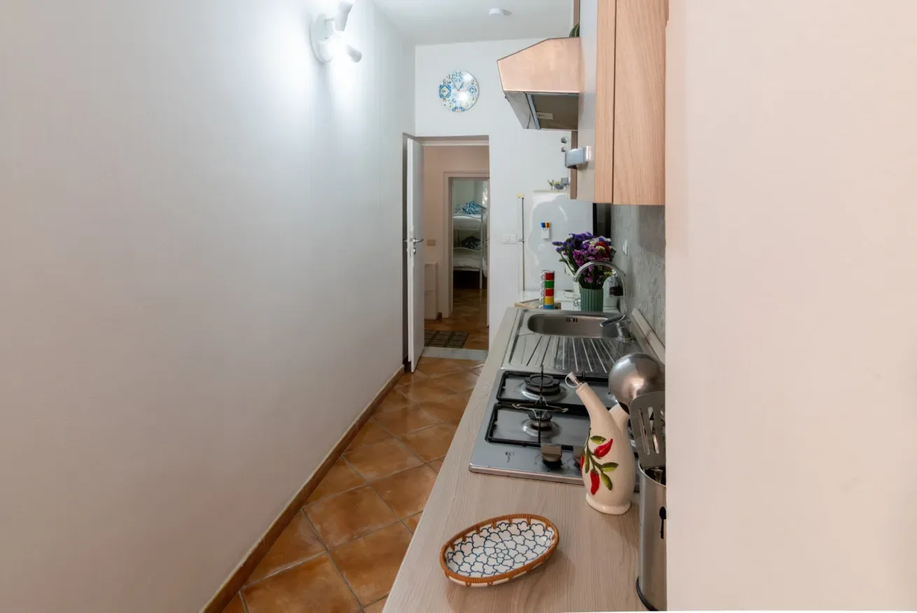 Una cocina estrecha con suelo de baldosas, placa de cocción y armarios.