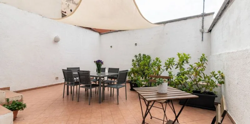 Un patio amurallado tiene una mesa de comedor, asientos al aire libre y plantas en macetas.
