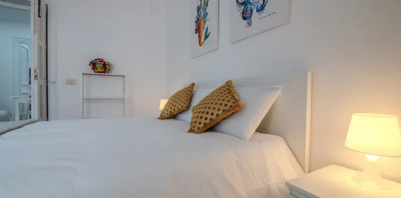 Un dormitorio luminoso con una cama bien hecha y cálida iluminación junto a la cama.