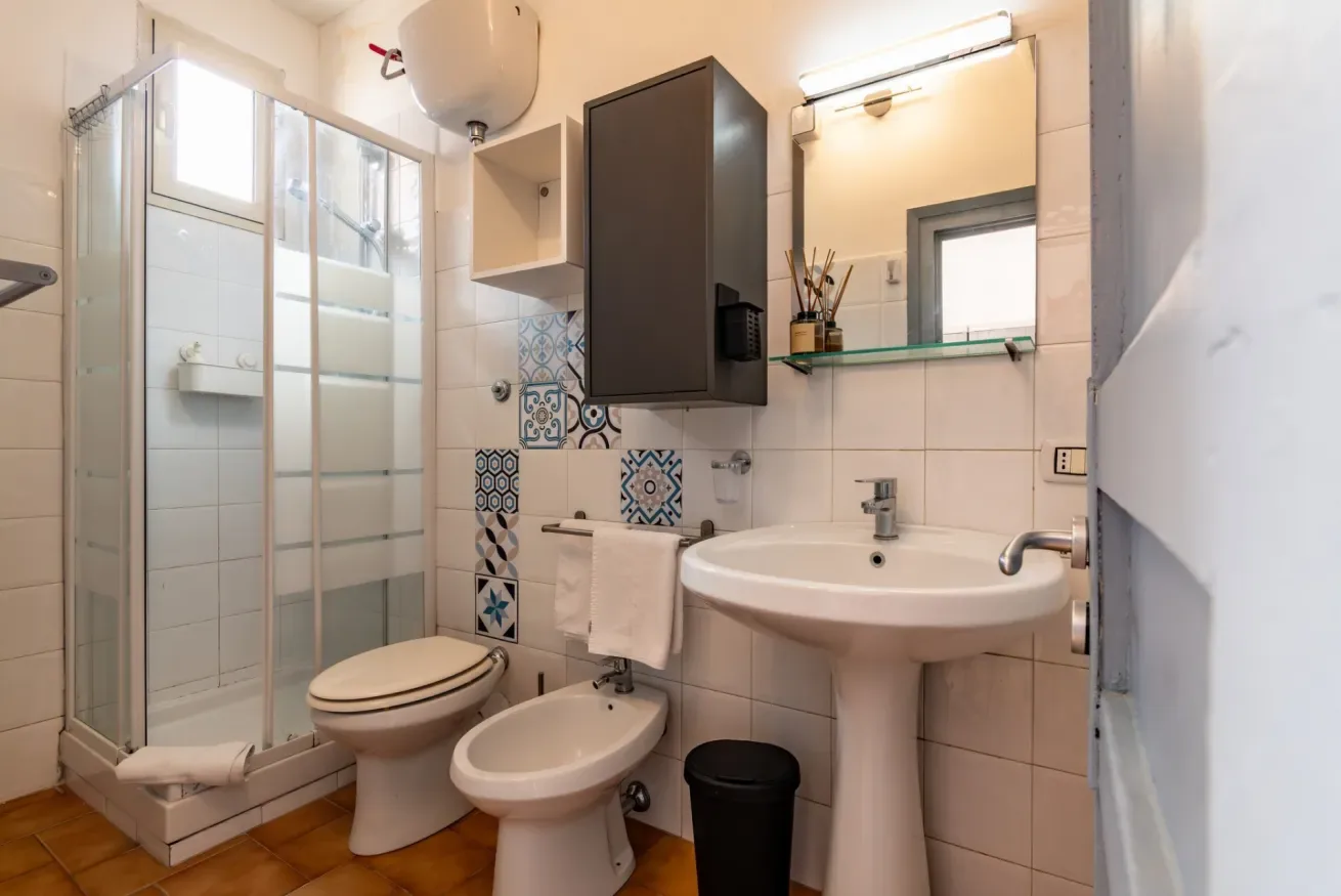 Un baño alicatado con ducha de vidrio, inodoro, bidé y lavabo.