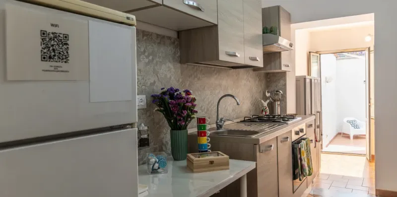 Una cocina compacta con refrigerador, encimera y zona de cocción.