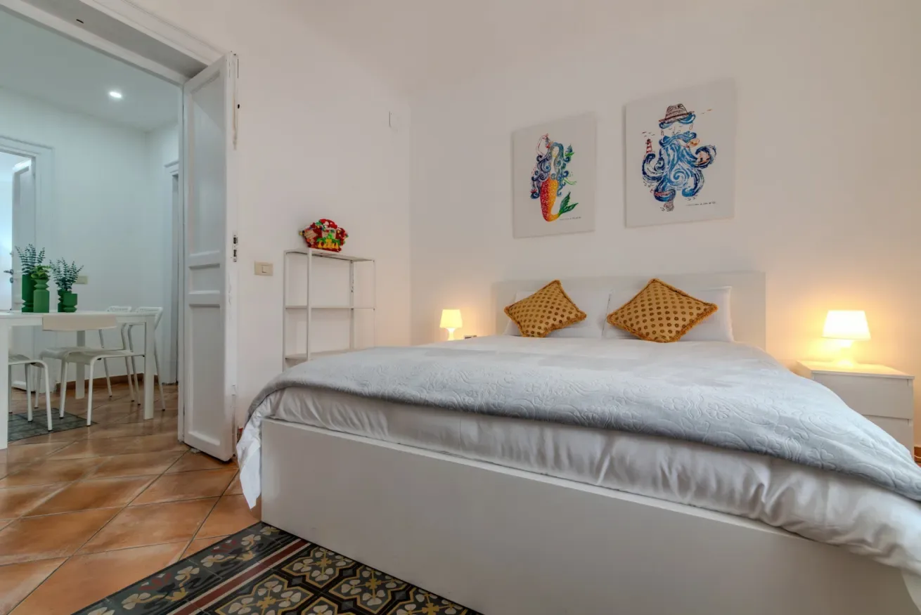 Un dormitorio con una cama grande, cojines estampados y cuadros sobre el cabecero.