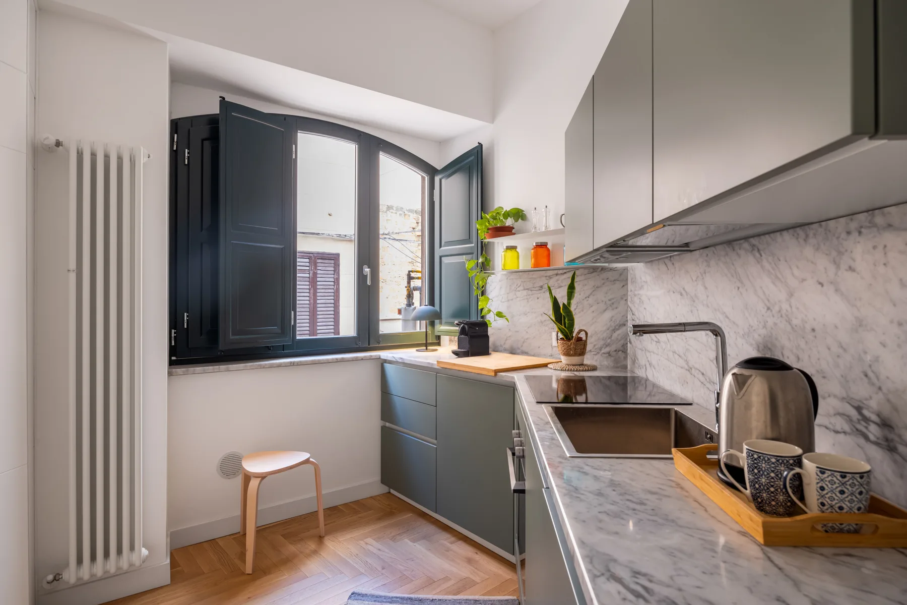 A bright kitchen with dark cabinetry, a marble-patterned counter, and an open window.