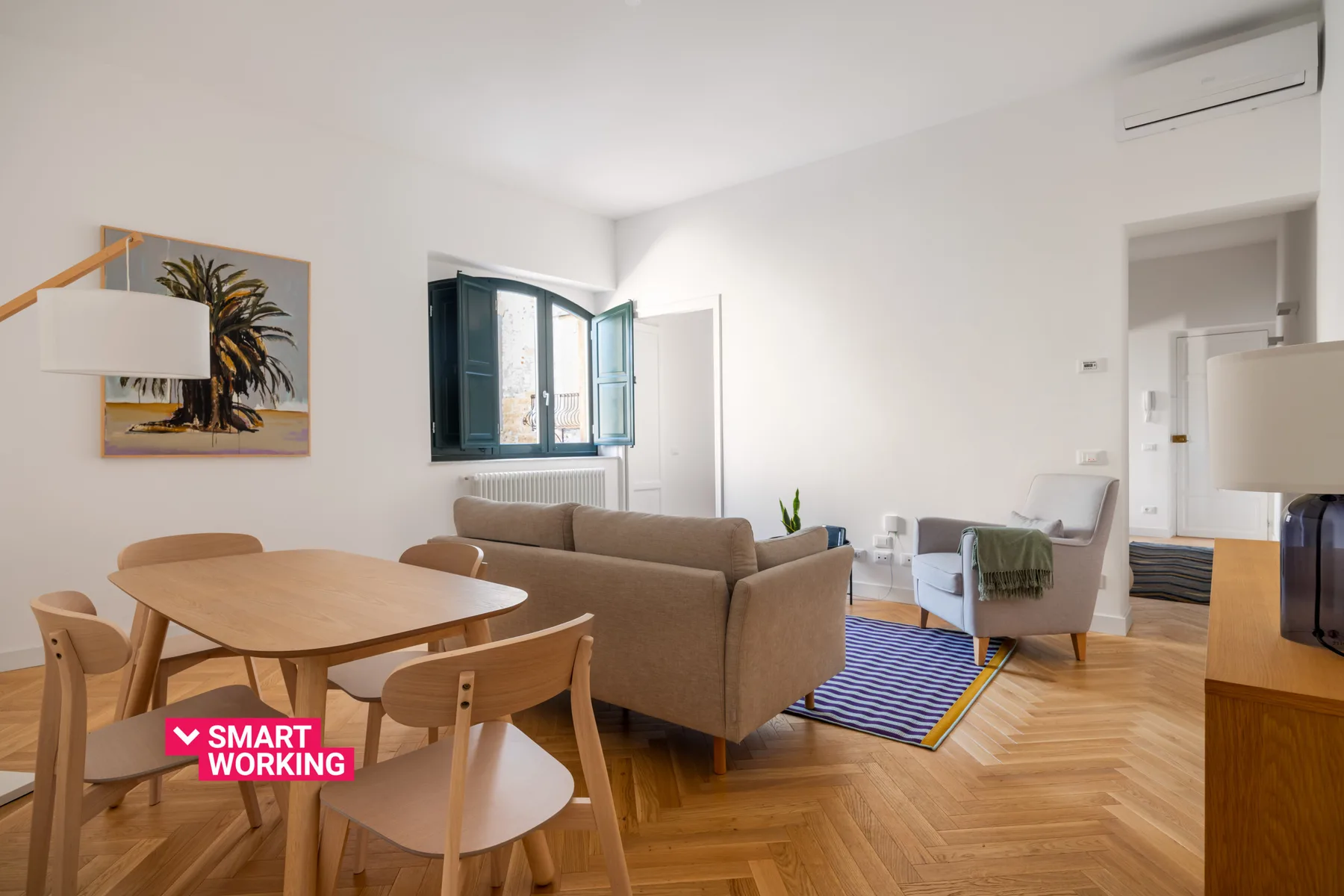 A bright living and dining area with seating, a table, and large windows.