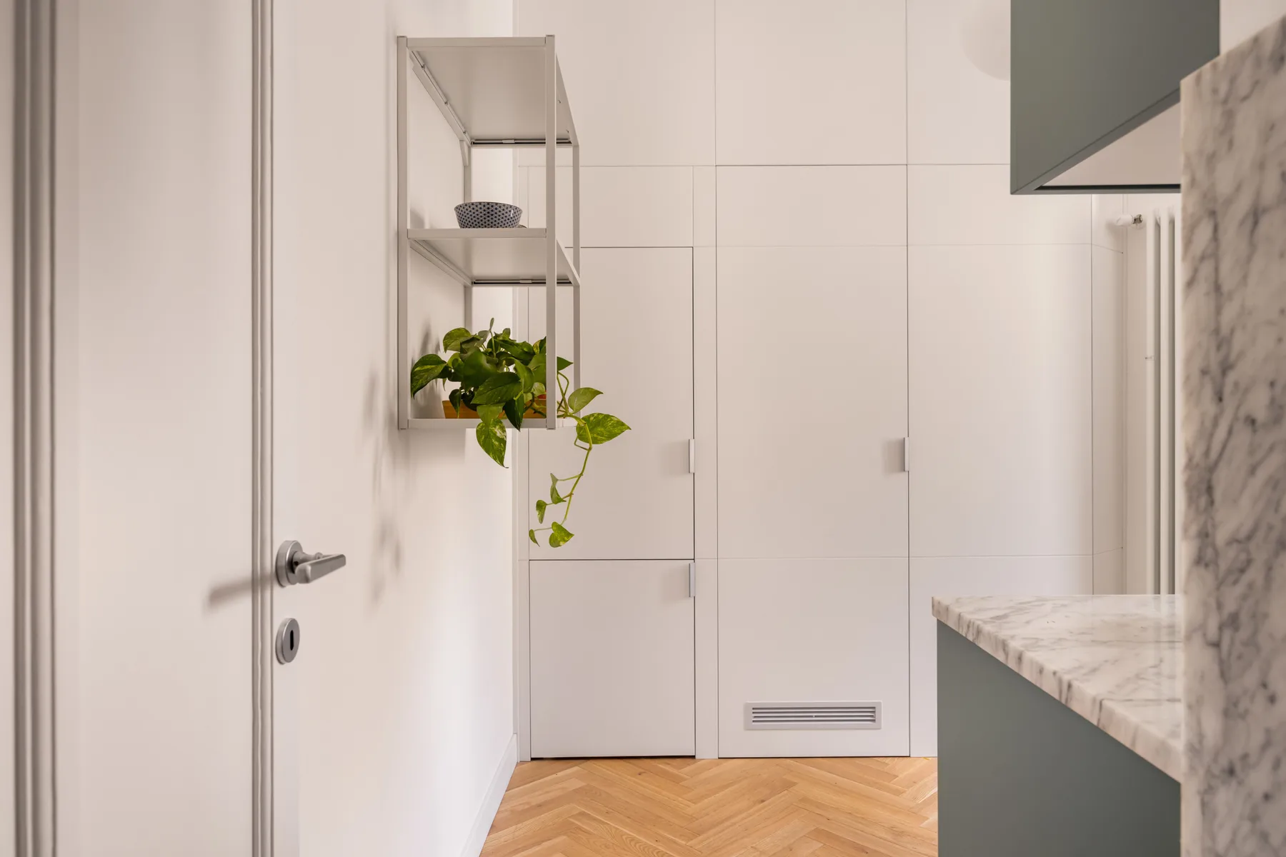 A bright interior hallway with a wall shelf holding a potted plant.