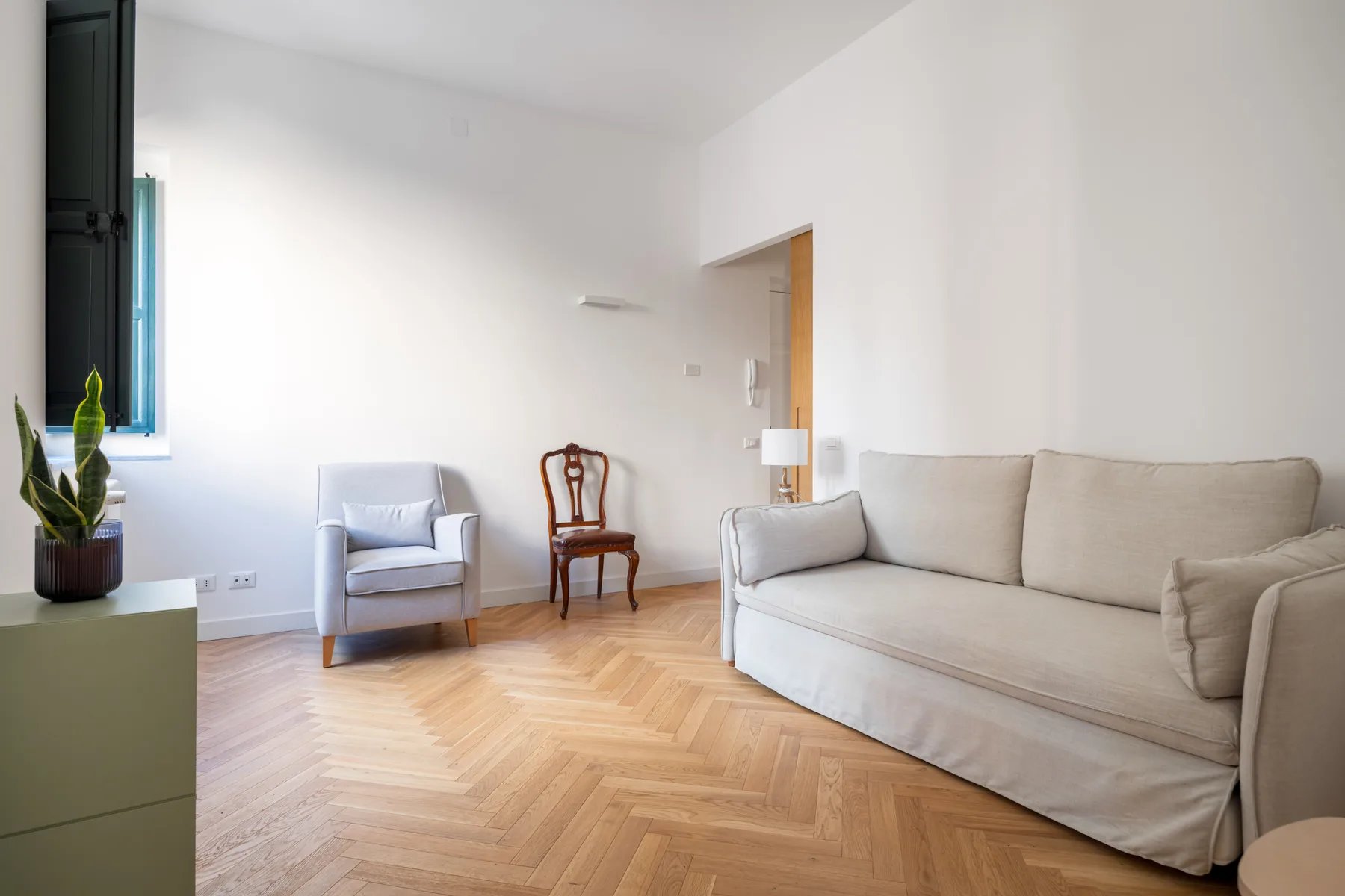 Living room with seating, a small side table, and a herringbone wood floor.