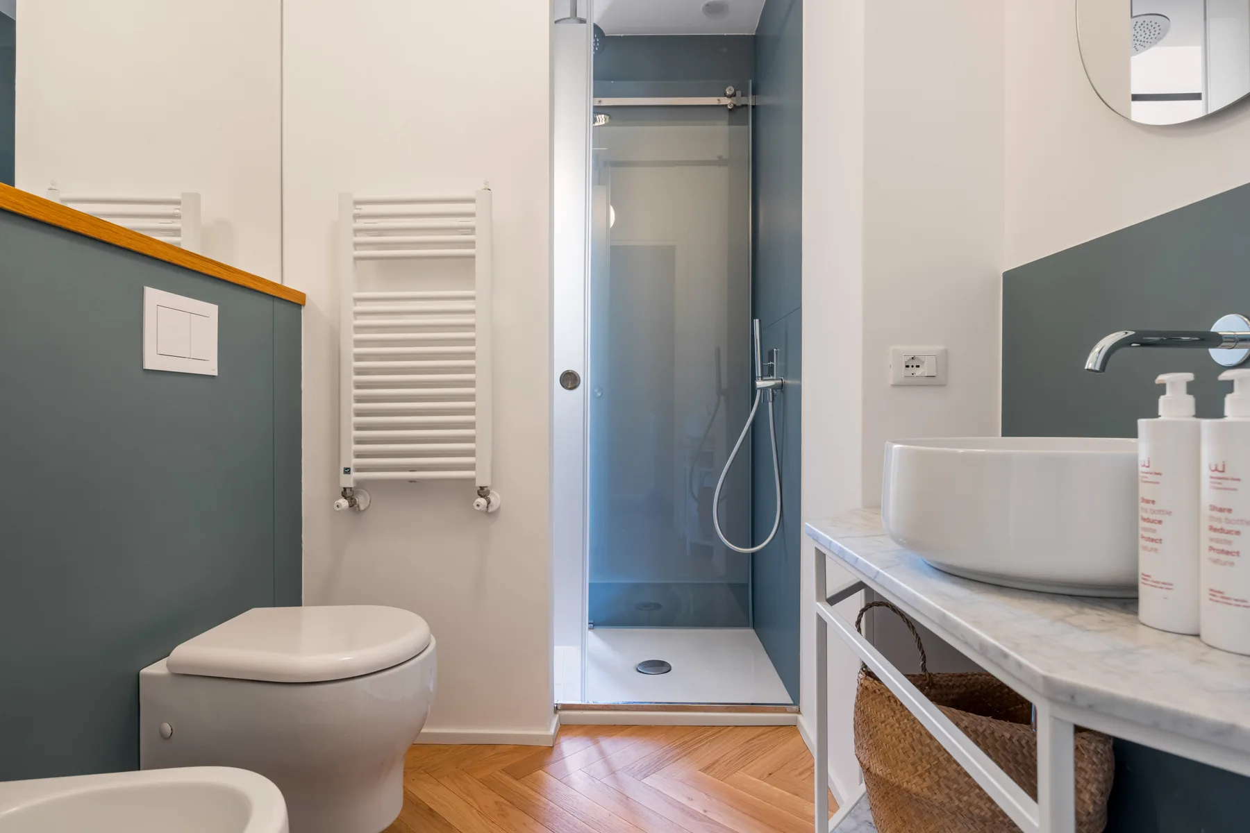 A bathroom with a glass shower, toilet, and sink.