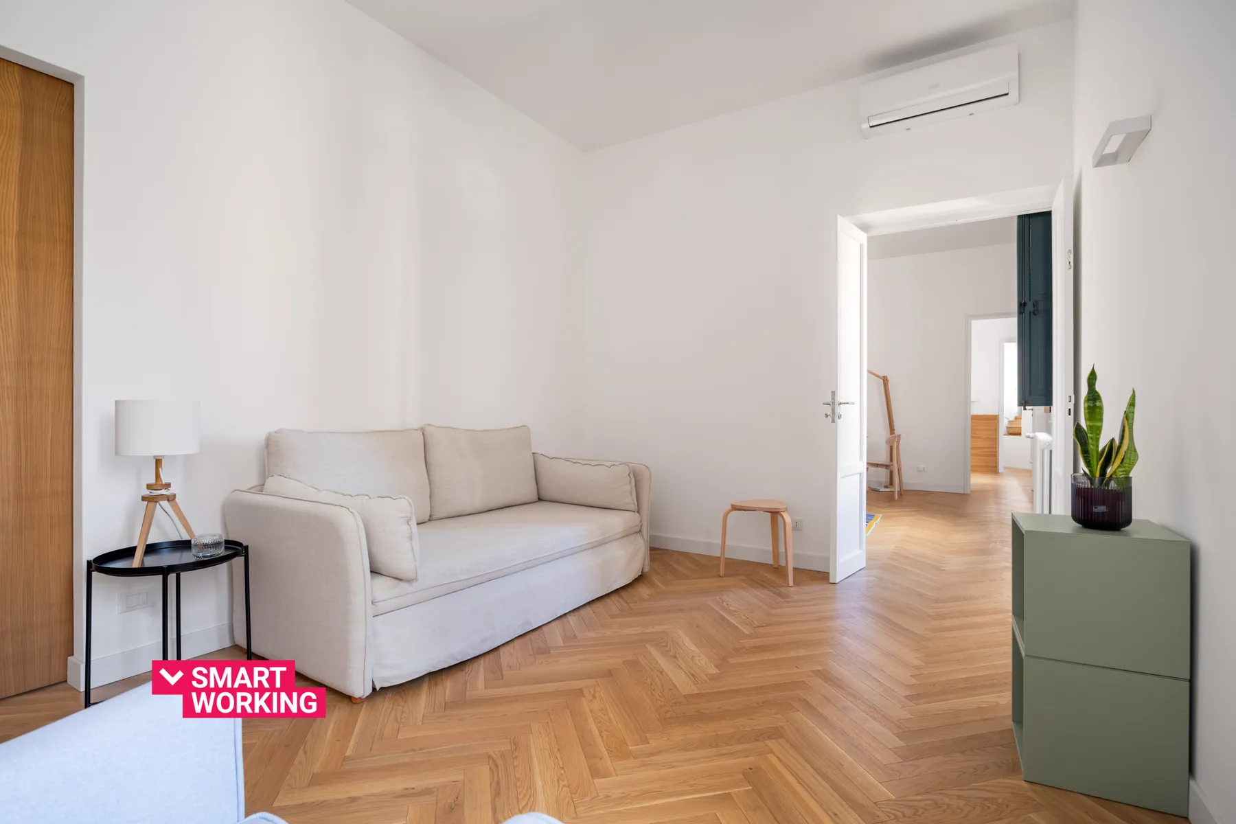 A bright living room with seating and a doorway opening into another room.