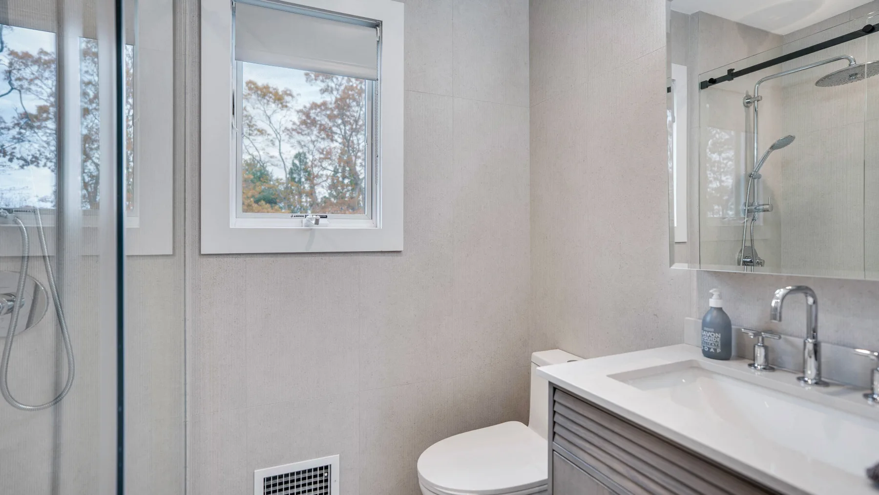 Un baño luminoso con lavabo, inodoro y ducha de cristal.