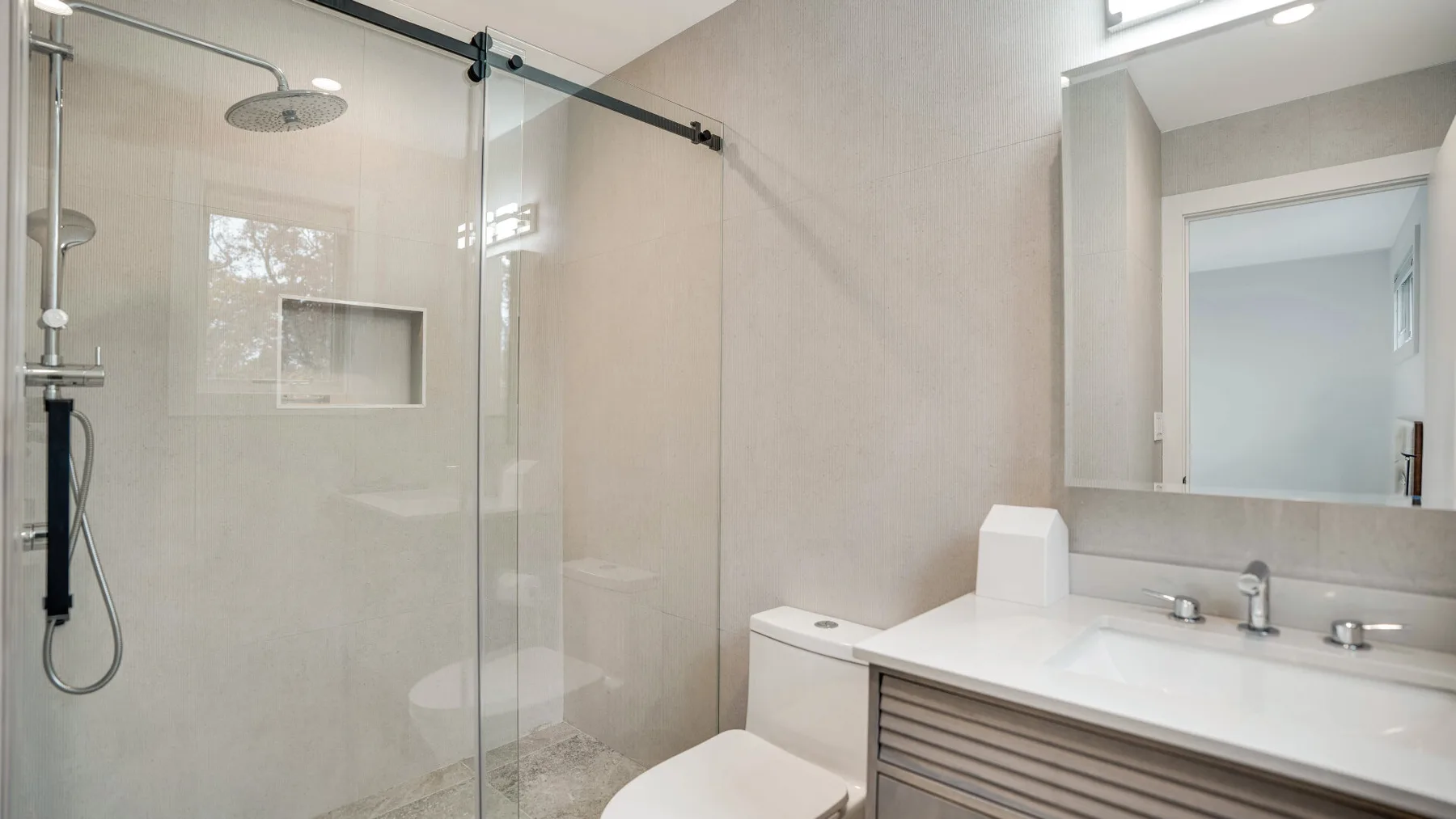 Un baño luminoso con ducha de vidrio y un amplio tocador.
