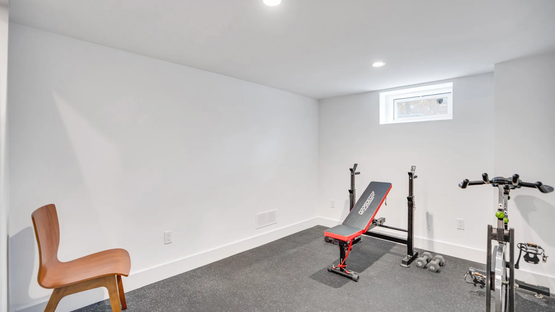 Un gimnasio en casa con un banco de ejercicio, pesas y equipo fijo.