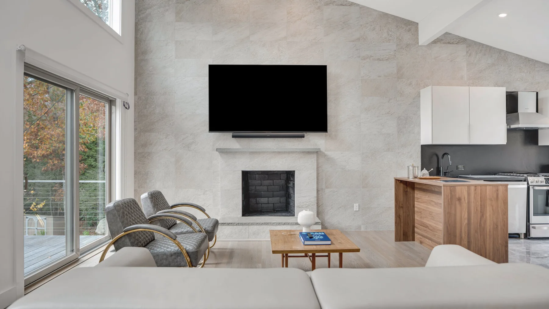 Una sala luminosa con chimenea, asientos y una cocina abierta.