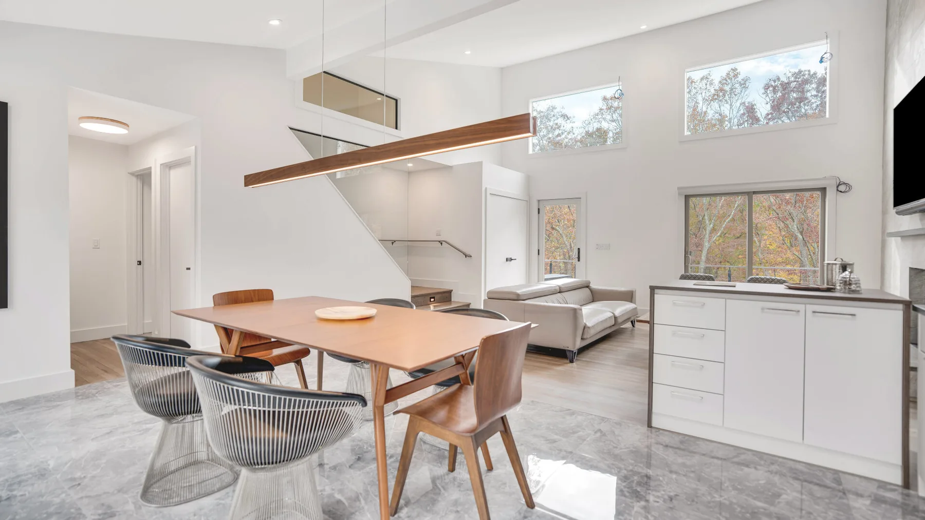 Una luminosa zona abierta de comedor y cocina con una mesa de madera y armarios blancos.