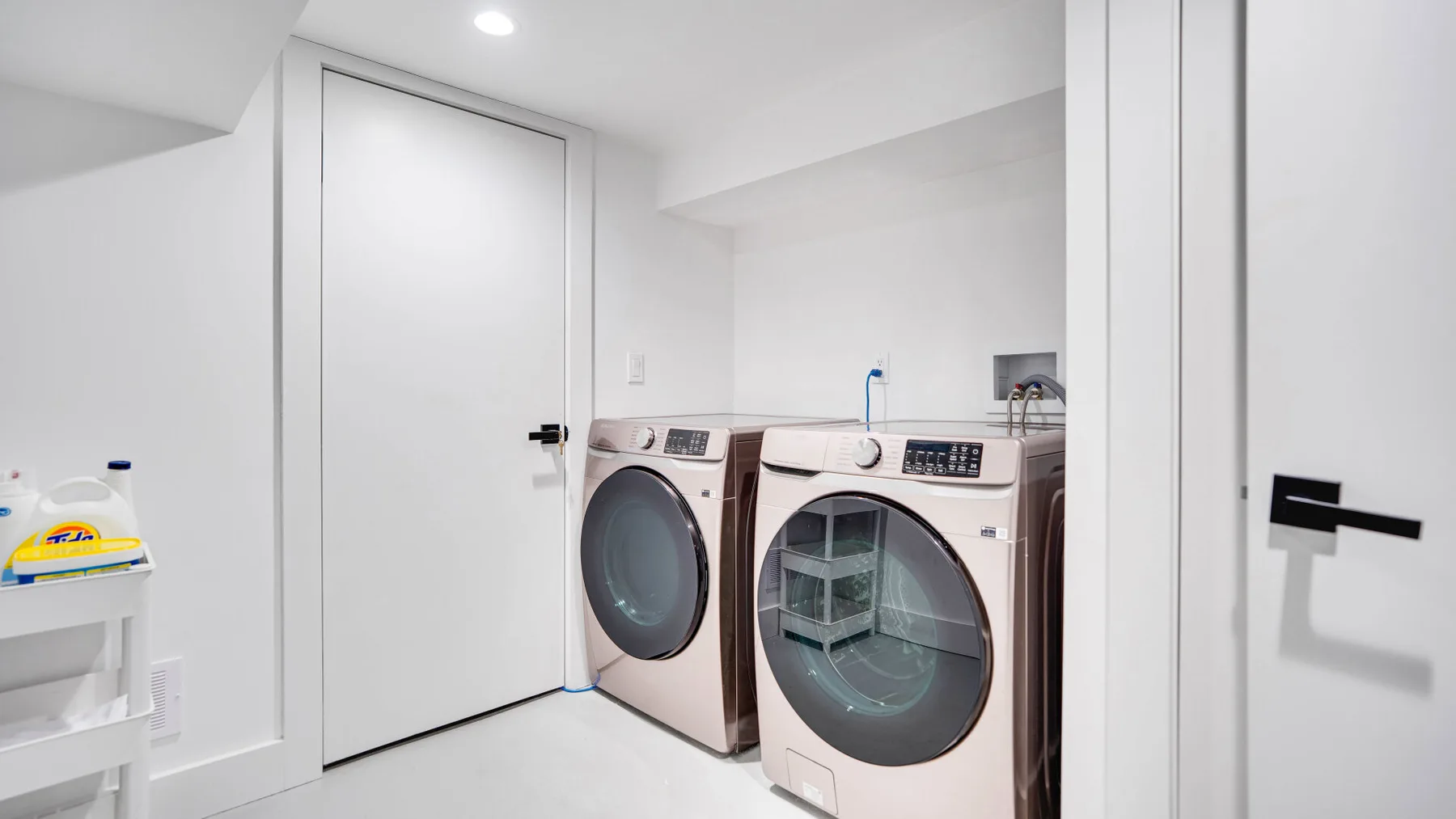 Un cuarto de lavandería con lavadora y secadora de carga frontal junto a una puerta cerrada.