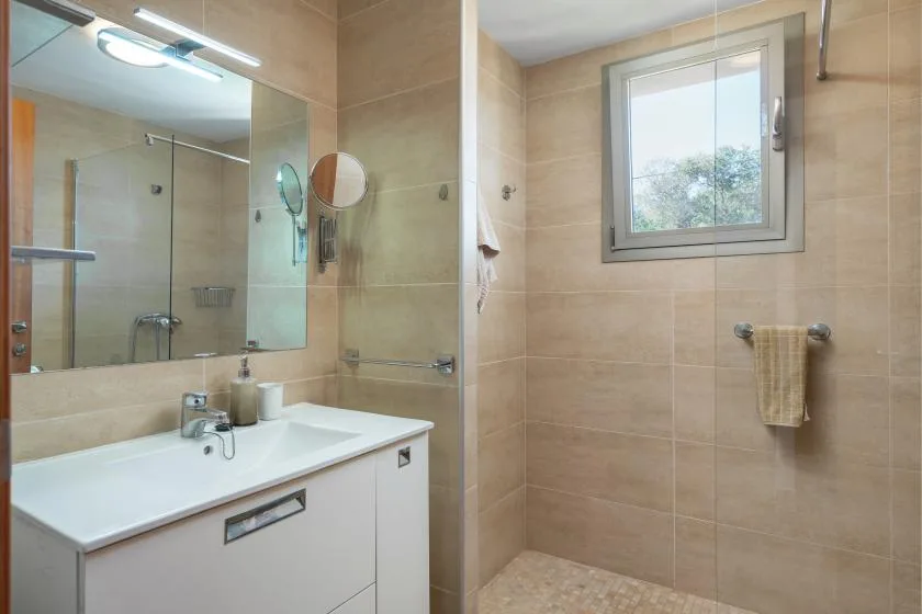 Un baño alicatado con lavabo, espejo y ventana.