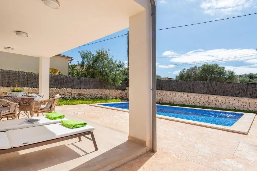 Un patio cubierto con asientos al aire libre da a una piscina.