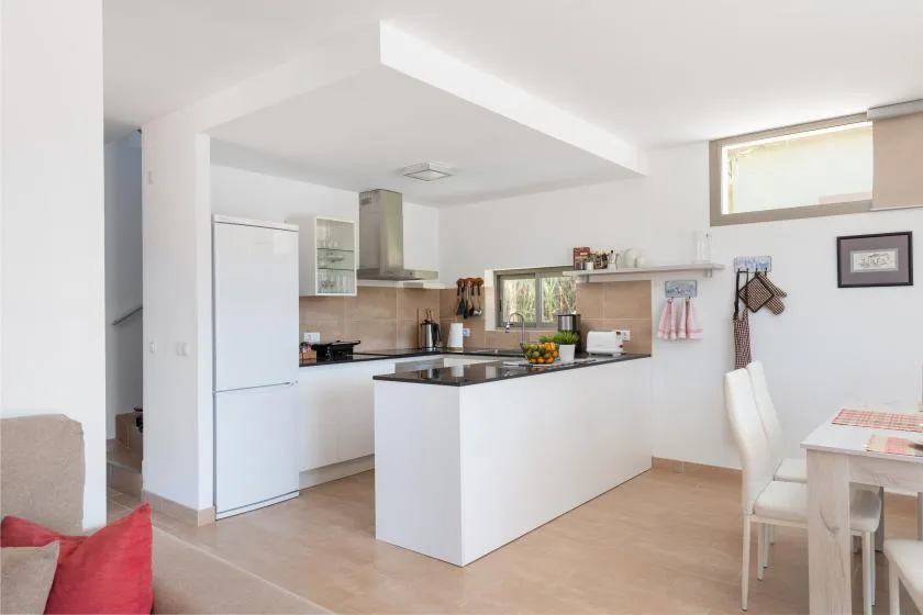 Una cocina luminosa con isla central se abre a un comedor.
