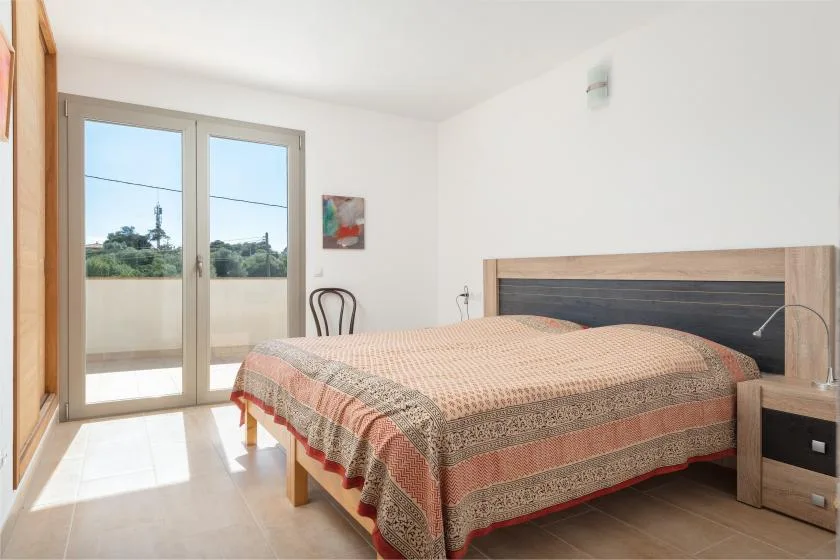 Un dormitorio con una cama y puertas de cristal que dan a un balcón.