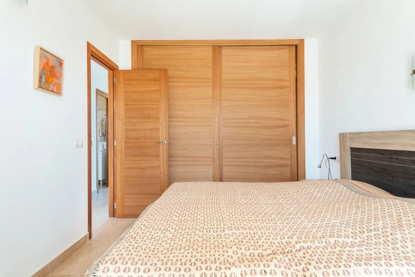 Un dormitorio con una colcha estampada y puertas de madera.