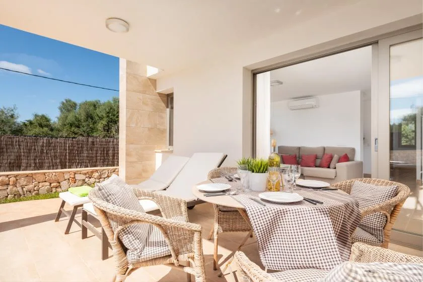 Una luminosa zona de comedor al aire libre con asientos tejidos da a un patio y jardín.