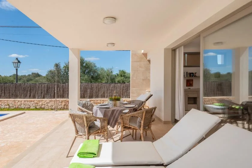 Un patio cubierto tiene una mesa de comedor y asientos junto a una piscina.