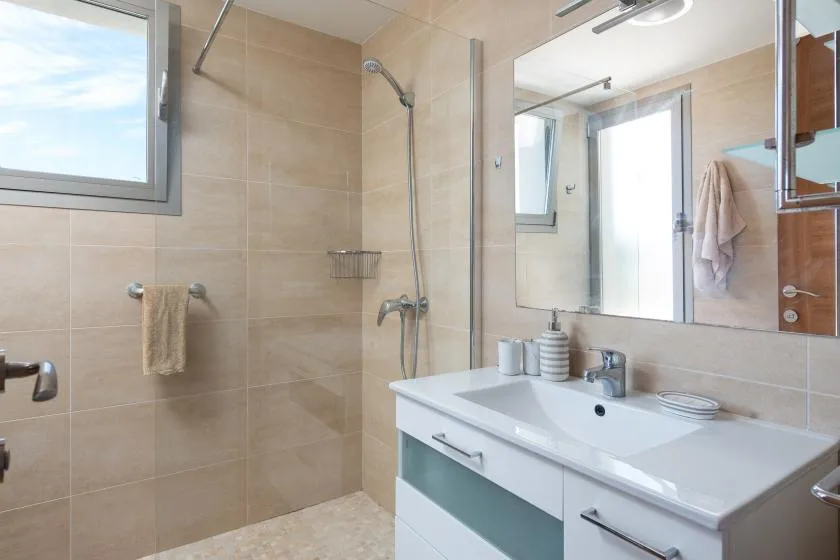 Un baño alicatado con una ducha de vidrio y un lavabo con mueble.