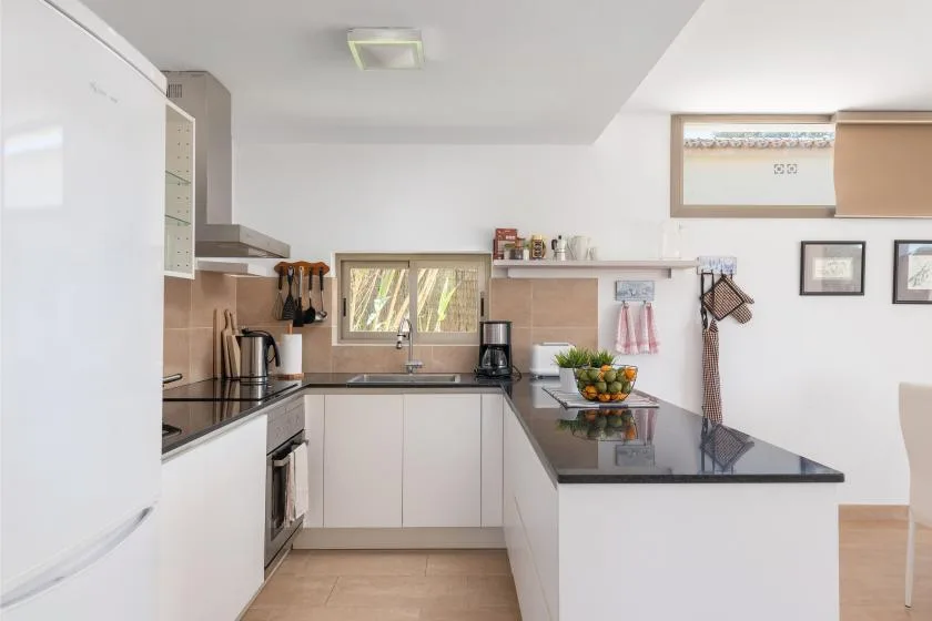 Una cocina luminosa con gabinetes blancos, un fregadero y una encimera central.