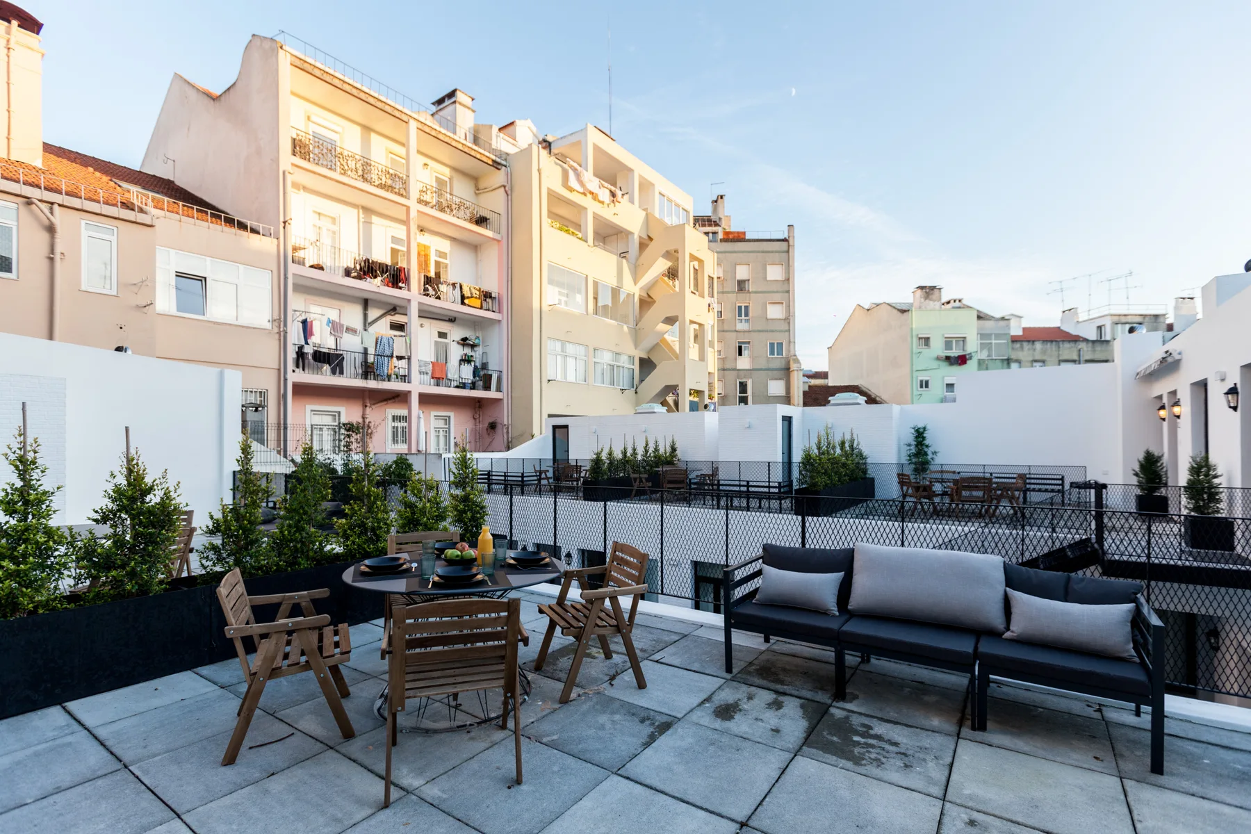 Terraza exterior con asientos y una mesa de comedor junto a edificios de apartamentos.