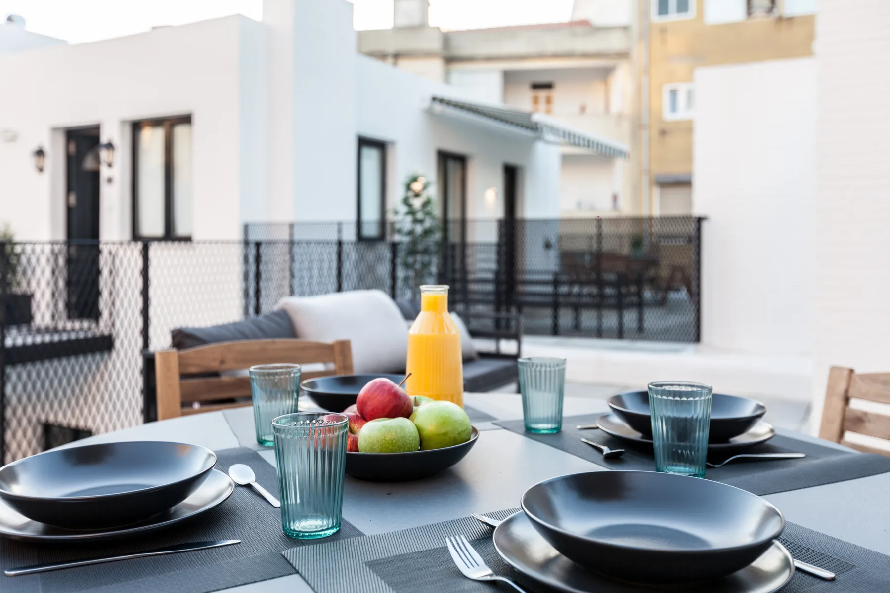 Comedor al aire libre con la mesa puesta y edificios cercanos a la vista.