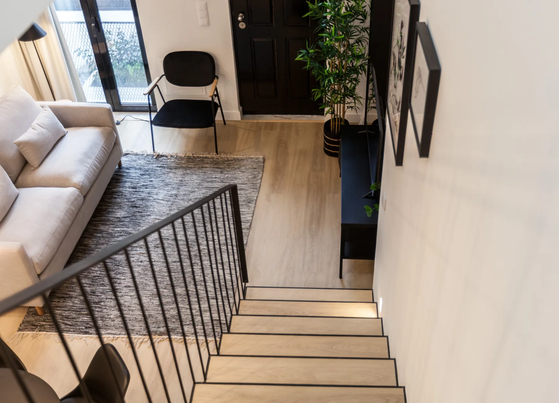 Una sala de estar con asientos y una alfombra junto a una escalera.