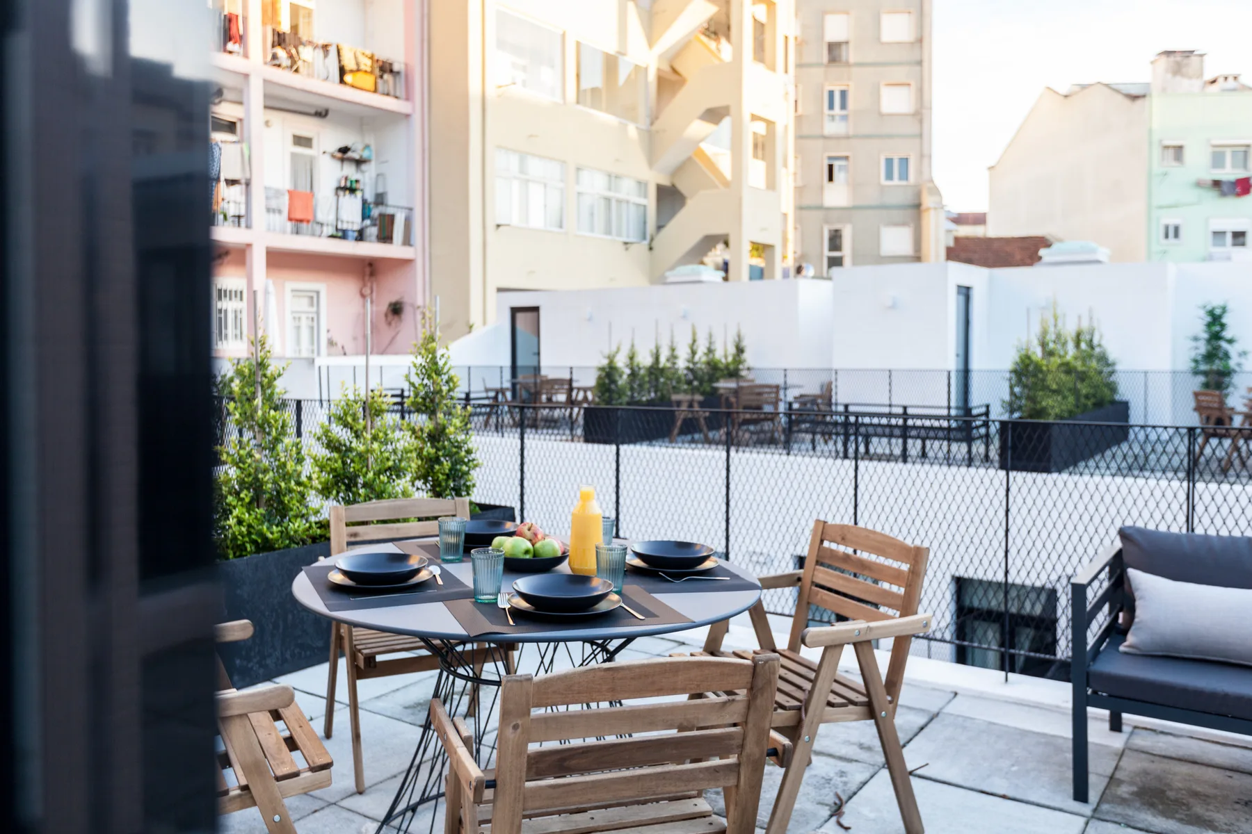 Una zona de comedor al aire libre con mesa y asientos junto a una terraza vallada.