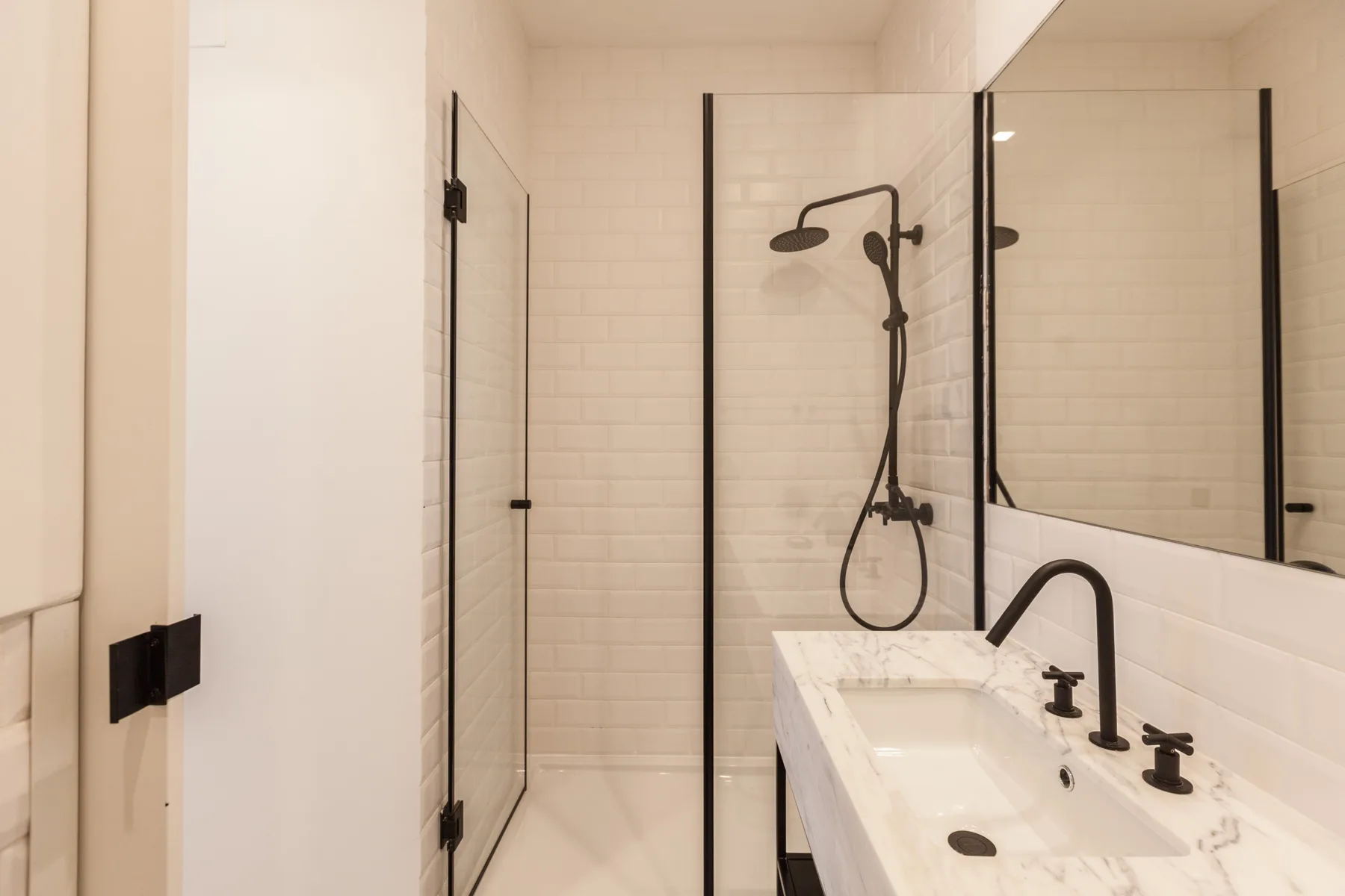 A bright bathroom with a glass shower and a sink beside a large mirror.