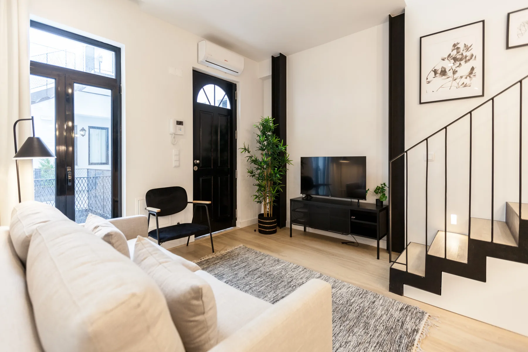 Una sala luminosa con asientos, un televisor y una escalera.