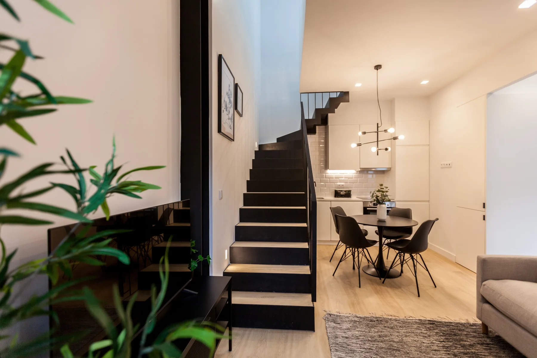 A modern interior with a staircase, dining table, and seating area.