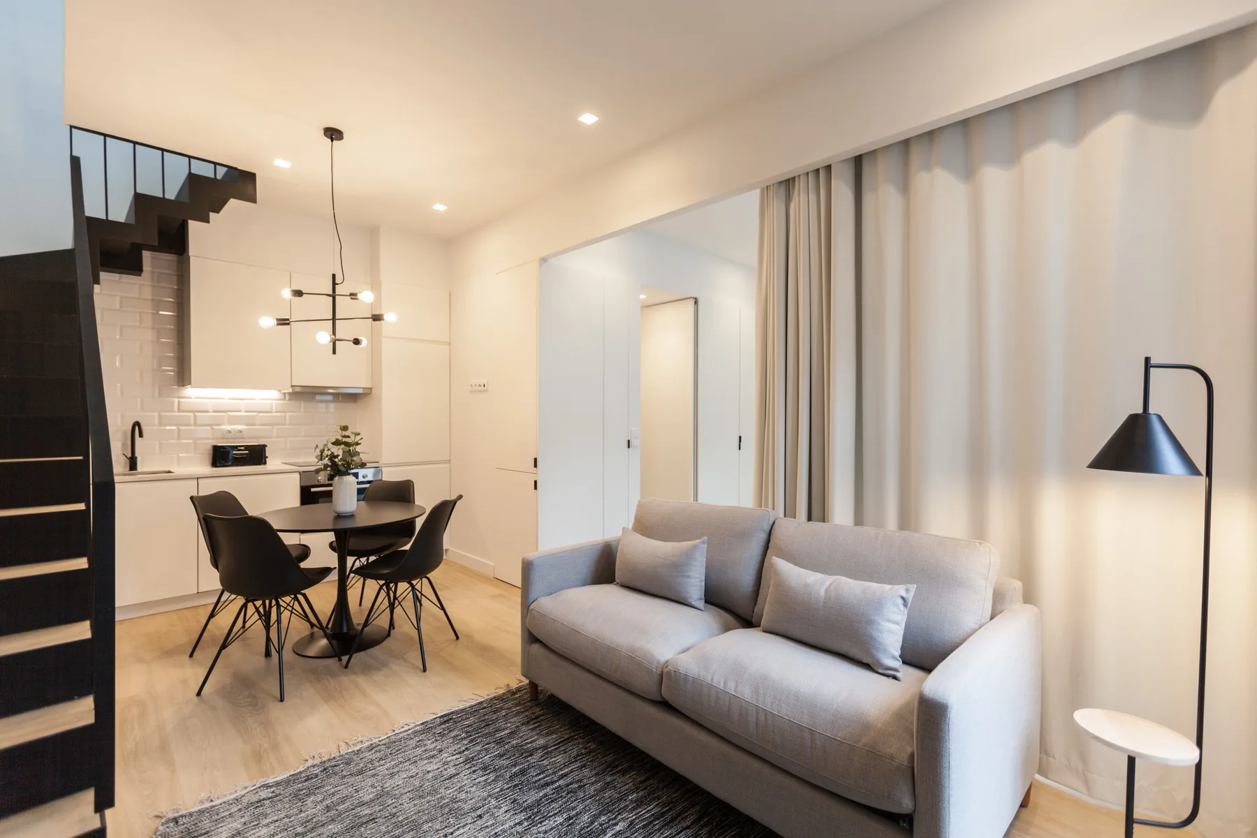 Una sala-comedor moderna con sofá, mesa y cocina abierta.
