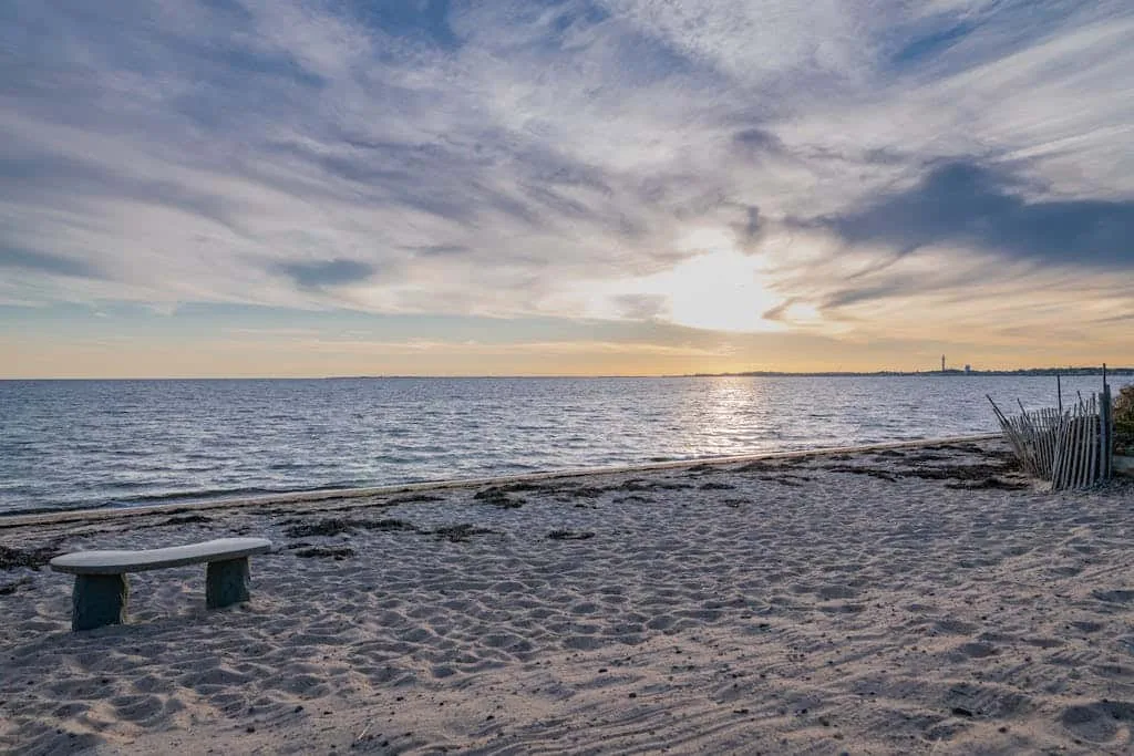 Una playa de arena mira al mar bajo un cielo nublado al atardecer.