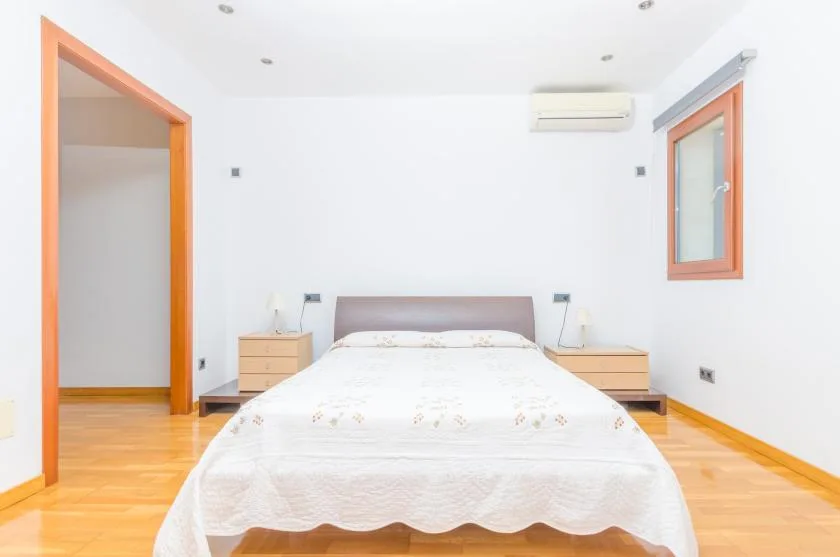 Un dormitorio luminoso con una cama entre dos mesitas de noche.