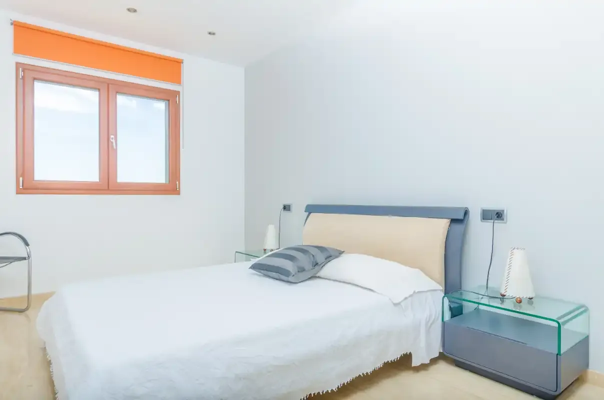 Un dormitorio con una cama bien hecha y una ventana.