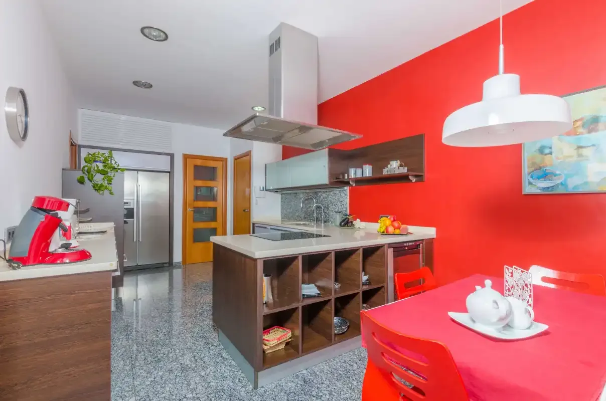 Una cocina moderna y comedor con una pared roja y una isla central.