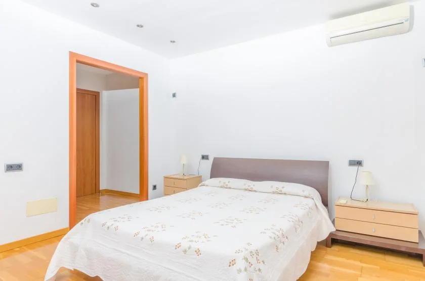 Un dormitorio luminoso con una cama doble y mesitas de noche de madera.