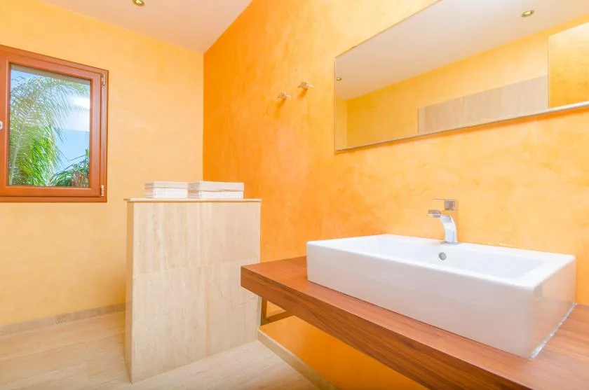 Un baño con un lavabo blanco sobre una encimera de madera y un espejo grande.