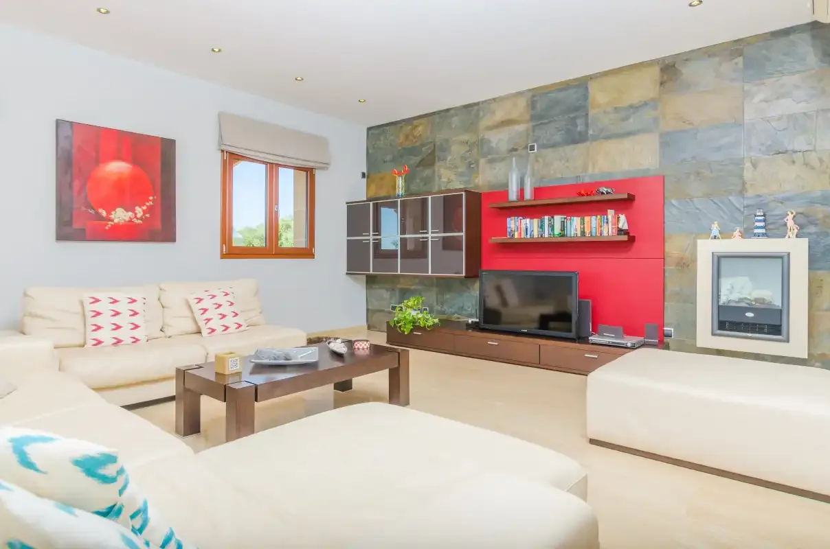 Una sala de estar con asientos claros, una mesa de centro y un televisor.